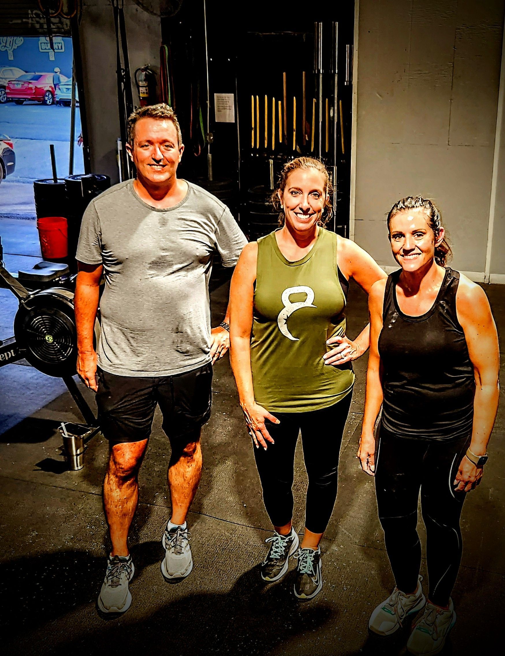 A man and two women are posing for a picture in a gym.