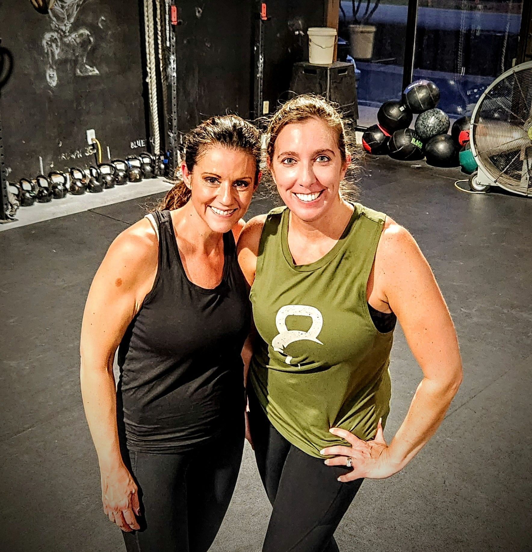 Two women are posing for a picture together in a gym