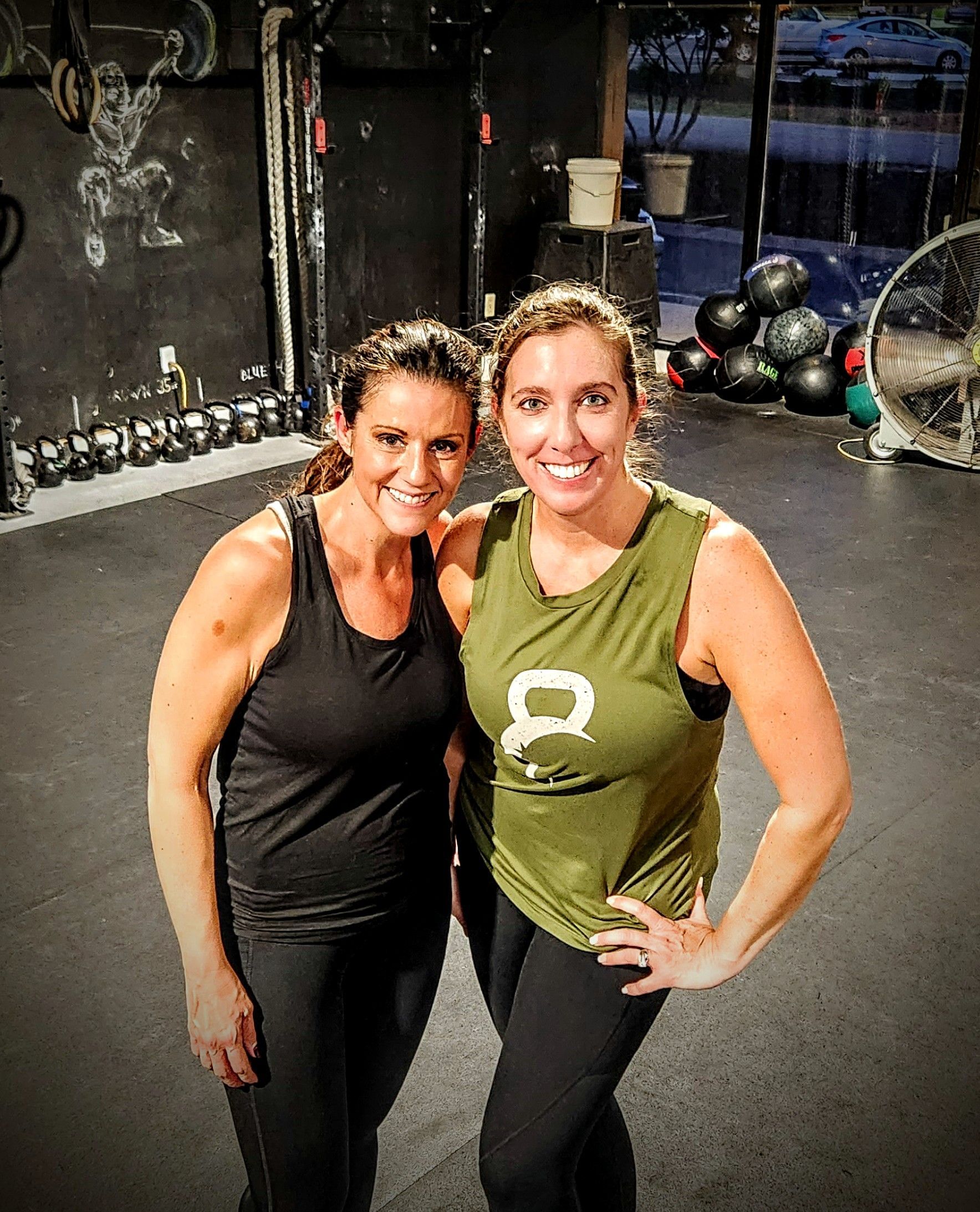 Two women are posing for a picture in a gym.