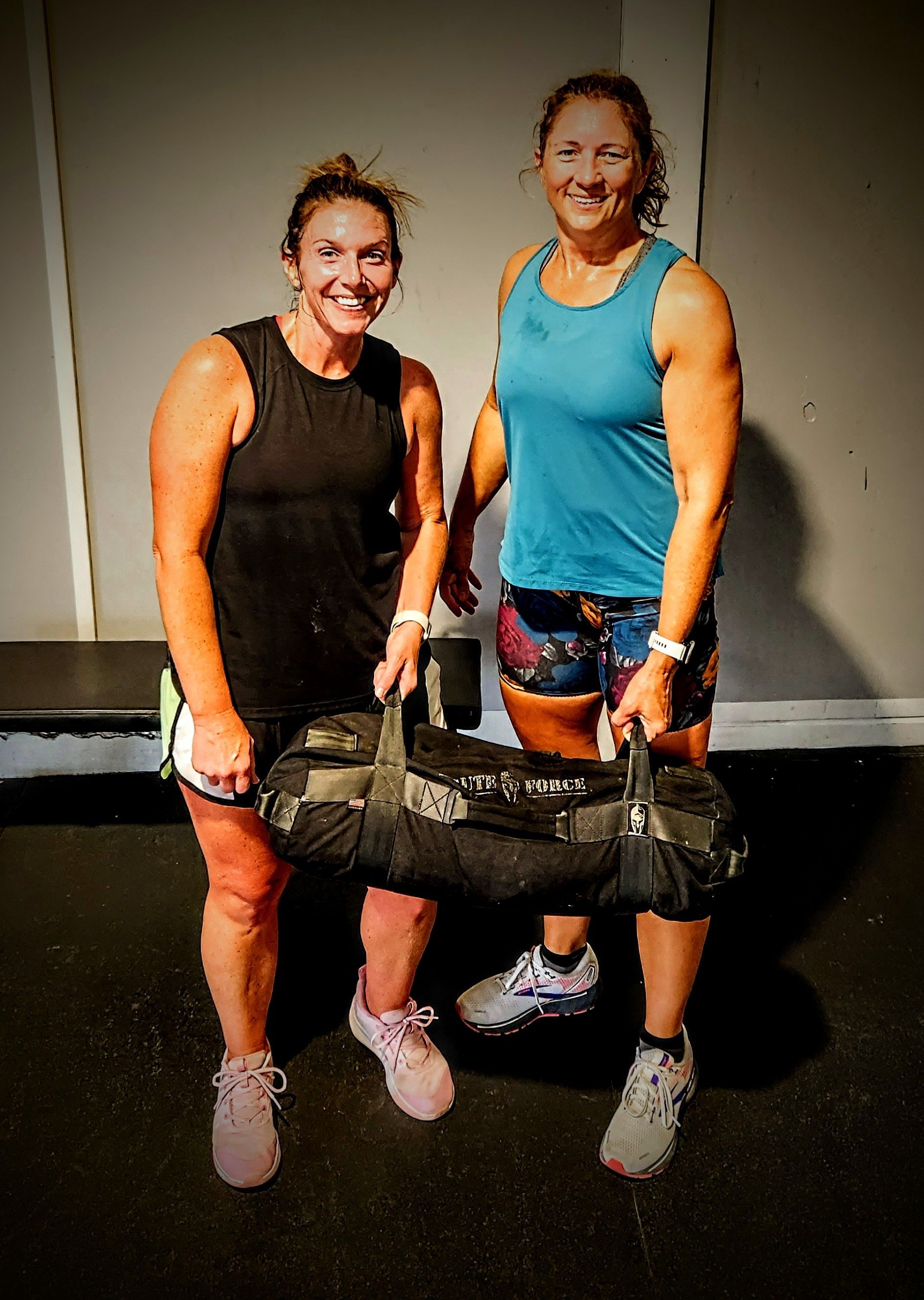 Two women are standing next to each other holding a bag.