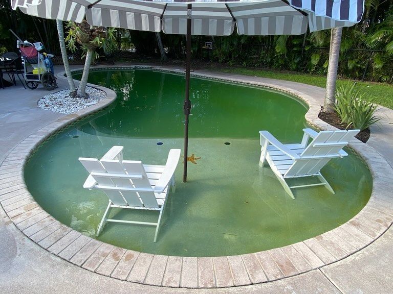A swimming pool with two chairs under an umbrella