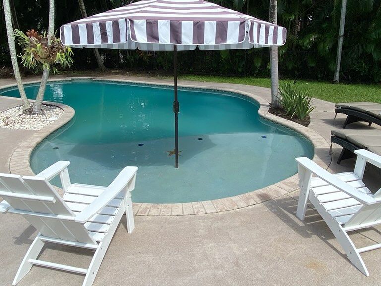 A striped umbrella sits next to a swimming pool