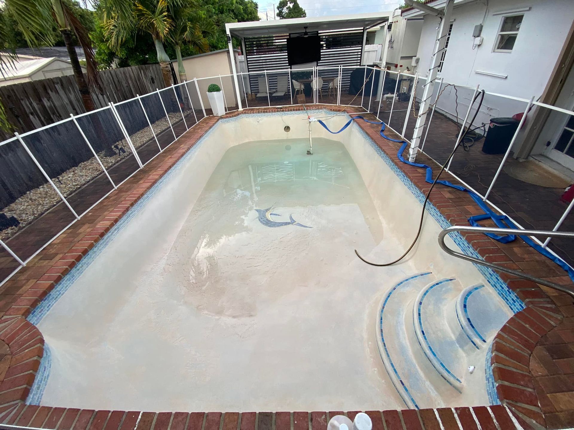 A large swimming pool with a fence around it and a house in the background.