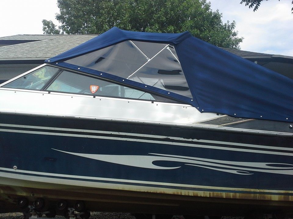 Small white and blue boat on a cradle in a shipyard under a partly cloudy sky