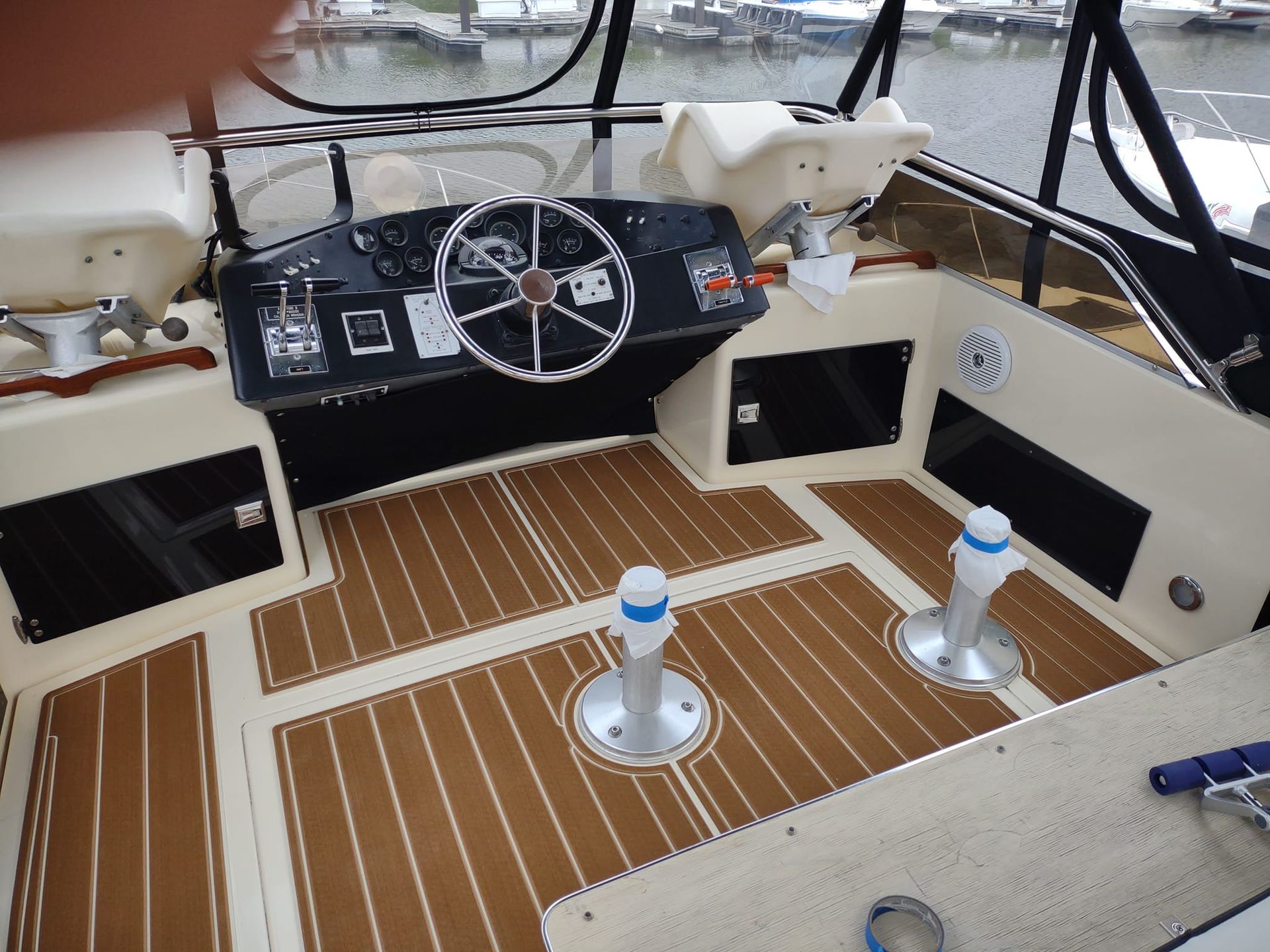 Wooden boat deck with coiled rope, white cleats, and a red-and-white life ring near the edge
