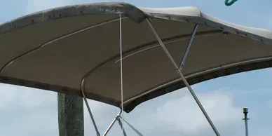 Gray canopy tent with metal support poles against a cloudy sky