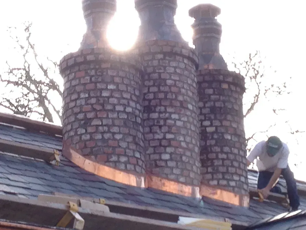 A Man Is Working on A Brick Chimney on A Roof | Santa Rosa, CA | Morris Heating and Sheet Metal