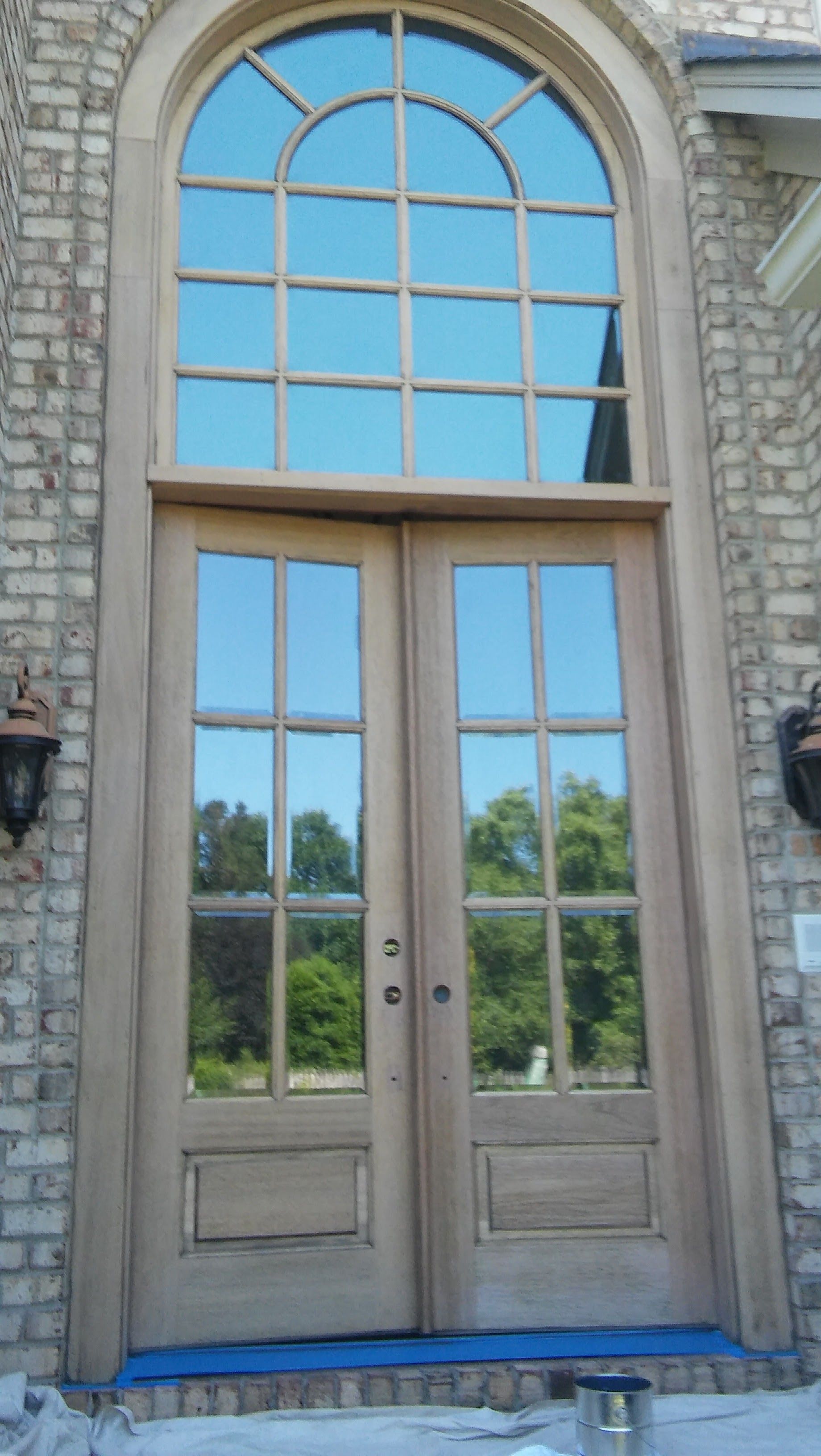 Double wooden doors with large arched window above; brick facade.
