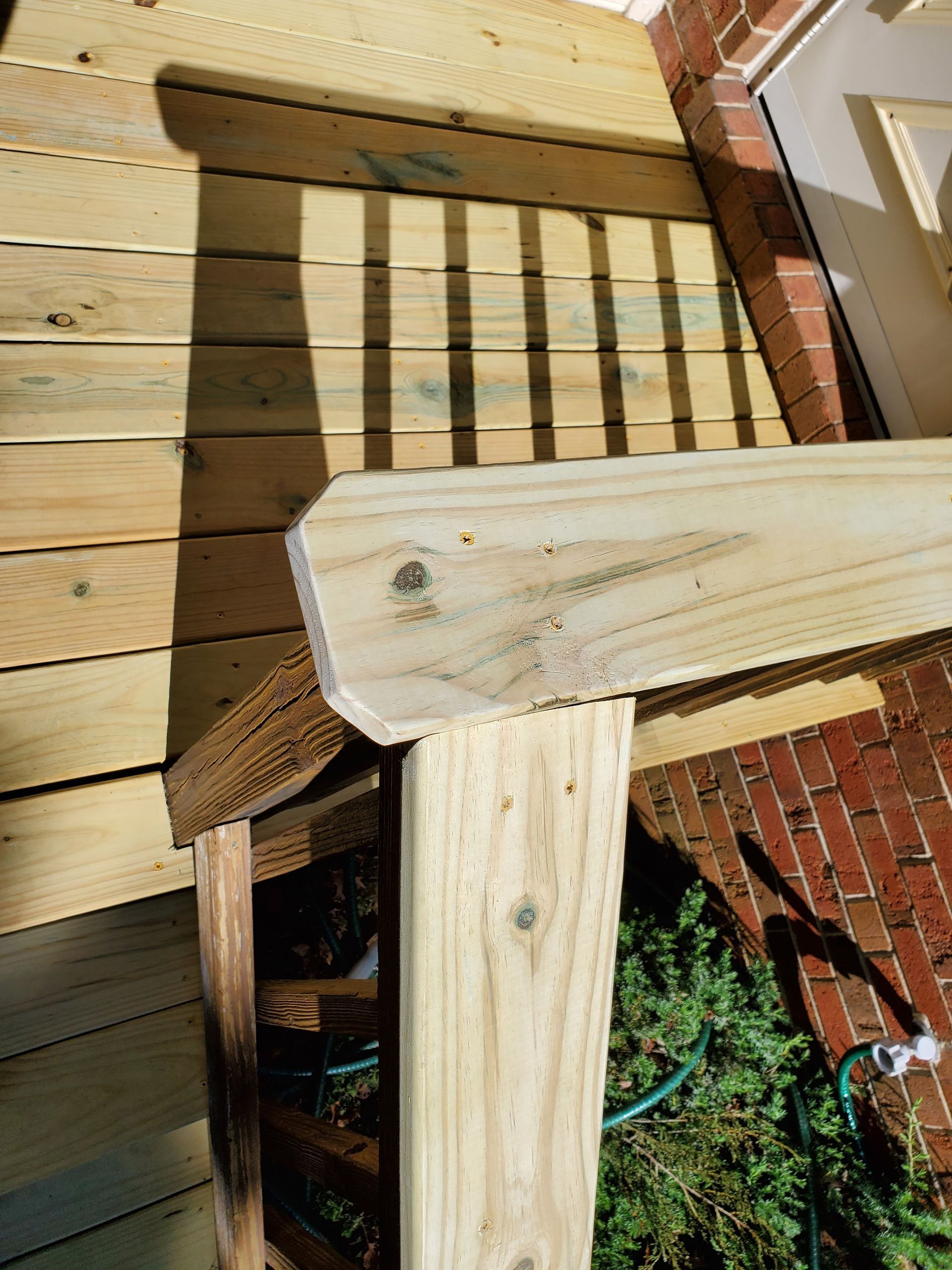Wooden deck with railing attached to a brick building.
