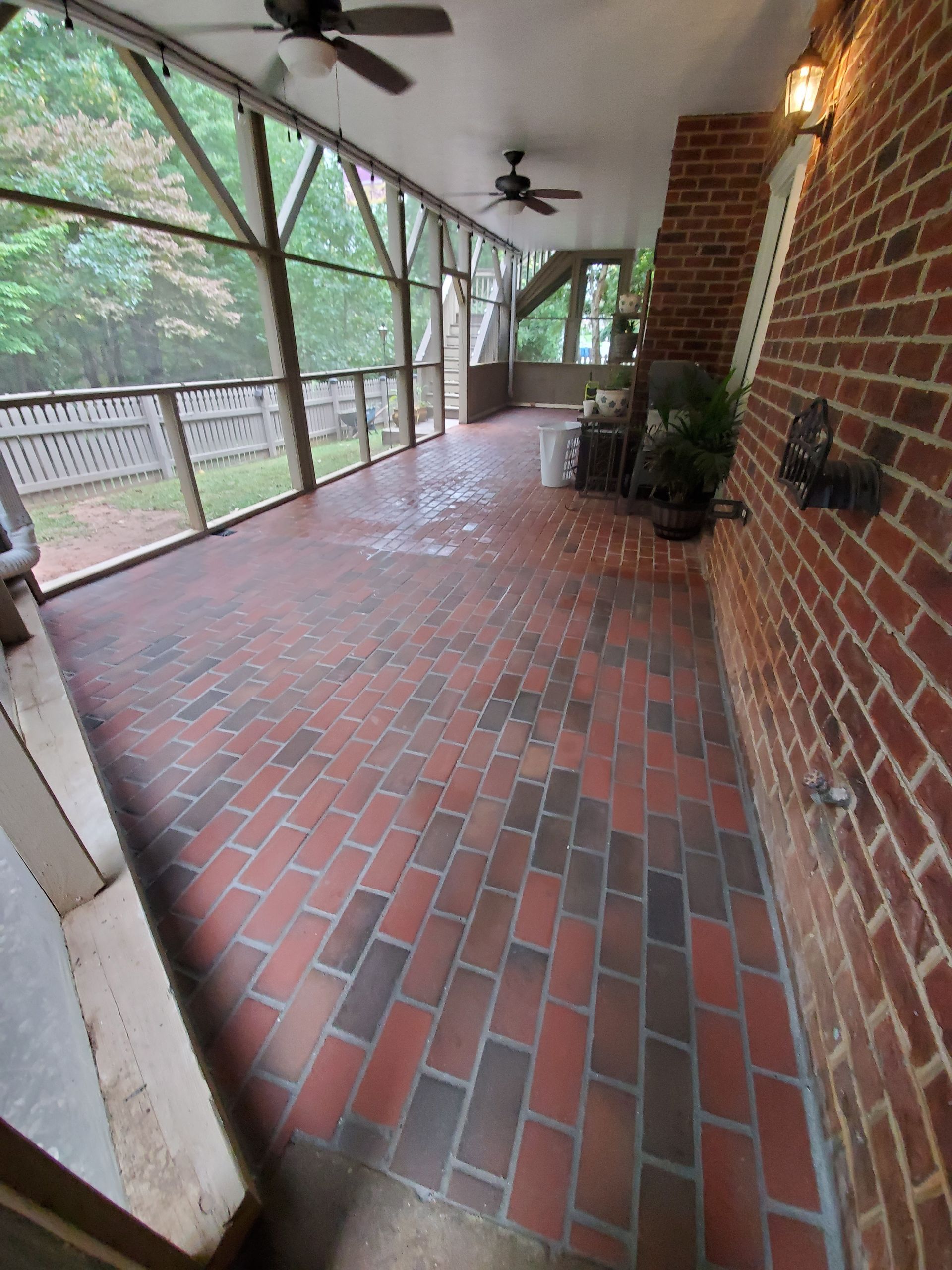 Brick-paved screened porch with a brick wall on the right and a view of the outside.