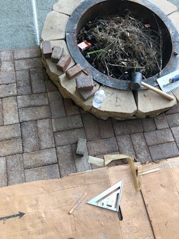 Fire pit surrounded by bricks, tools, and cardboard.