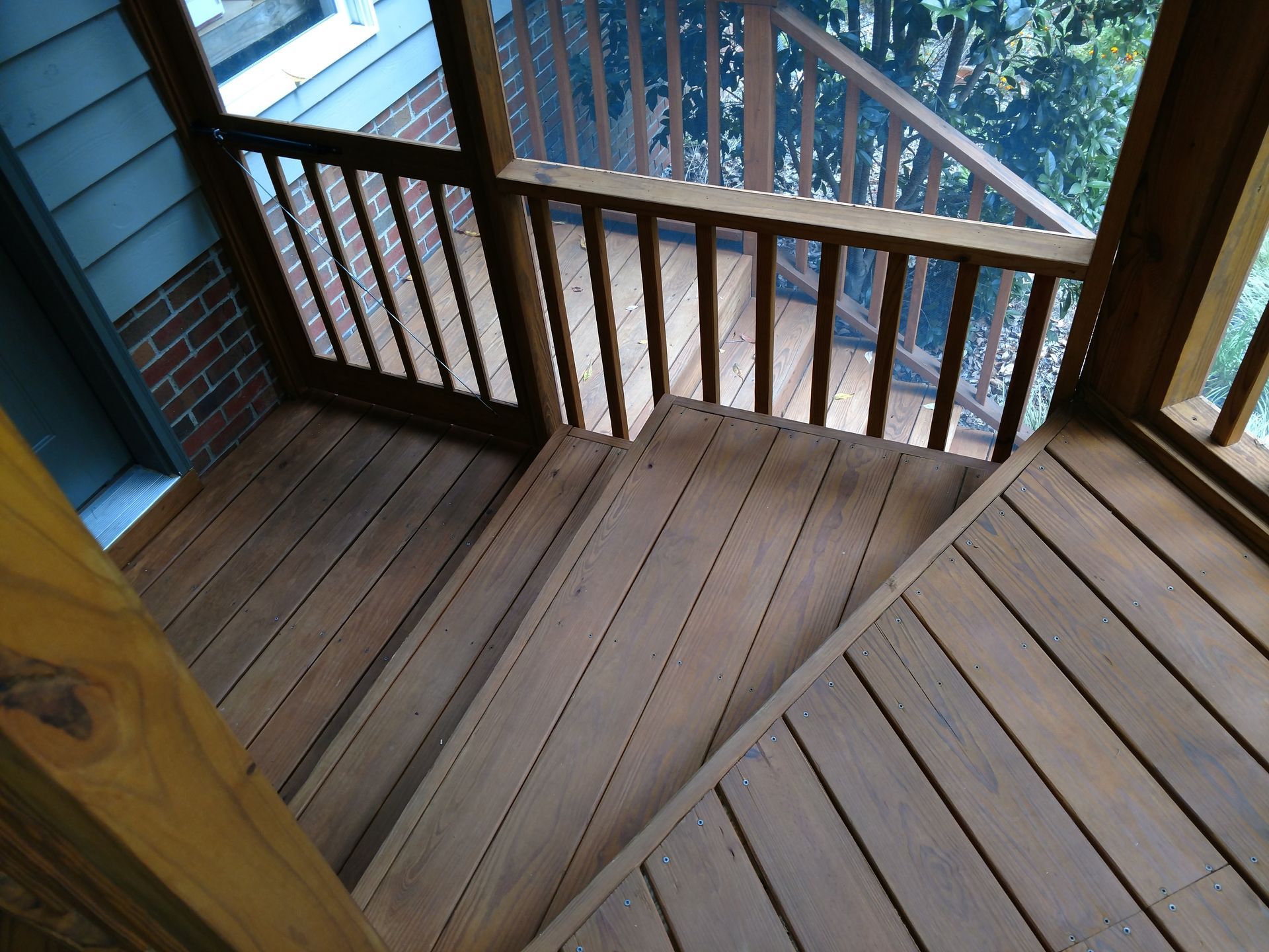 Wooden deck with steps, railings, and screened porch.