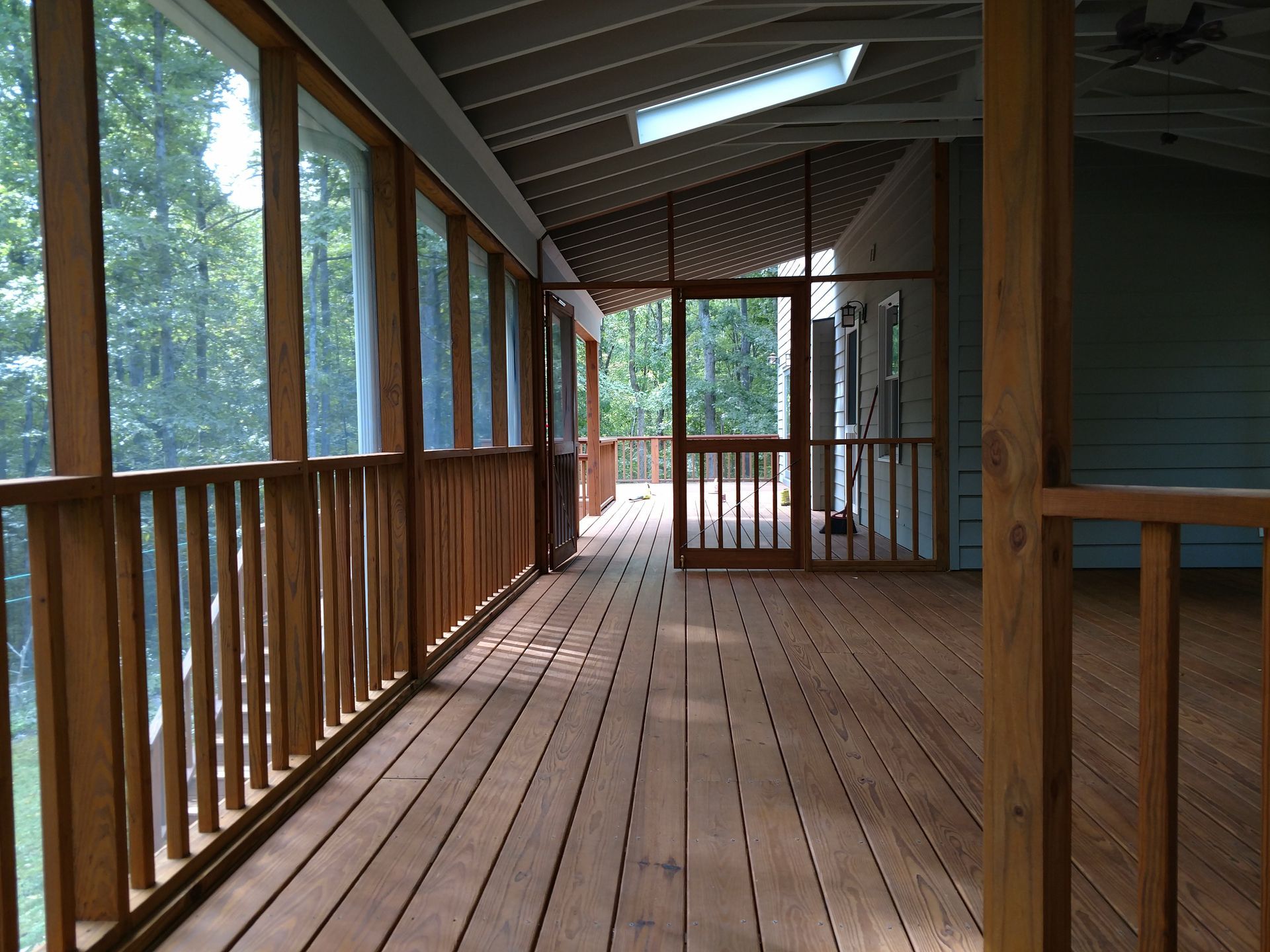 Wooden screened porch with railings, door, and natural light.