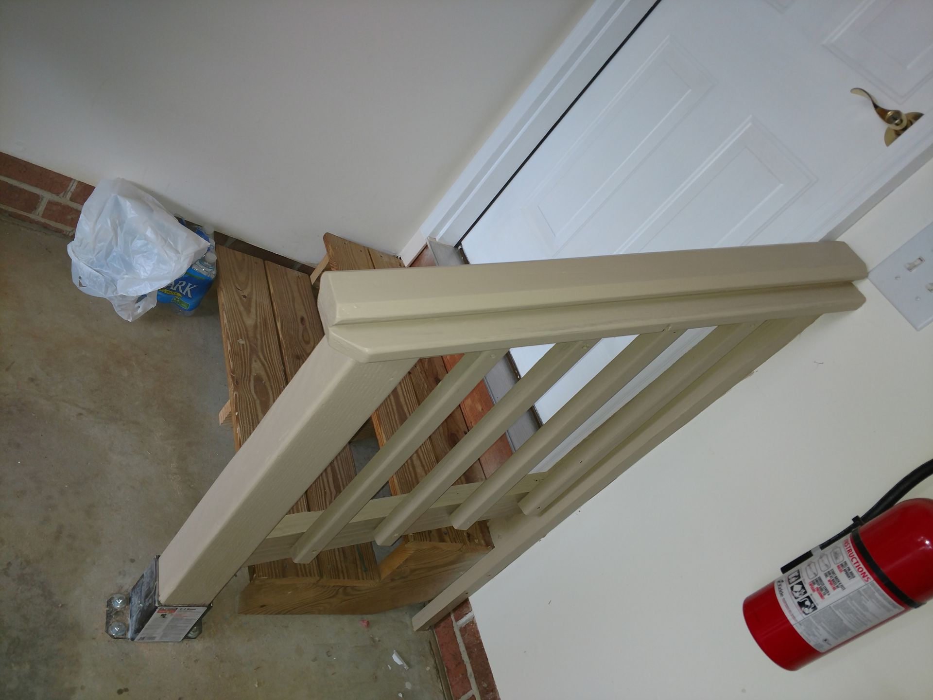 Staircase with railing leading up to a closed white door. Red fire extinguisher on the wall.