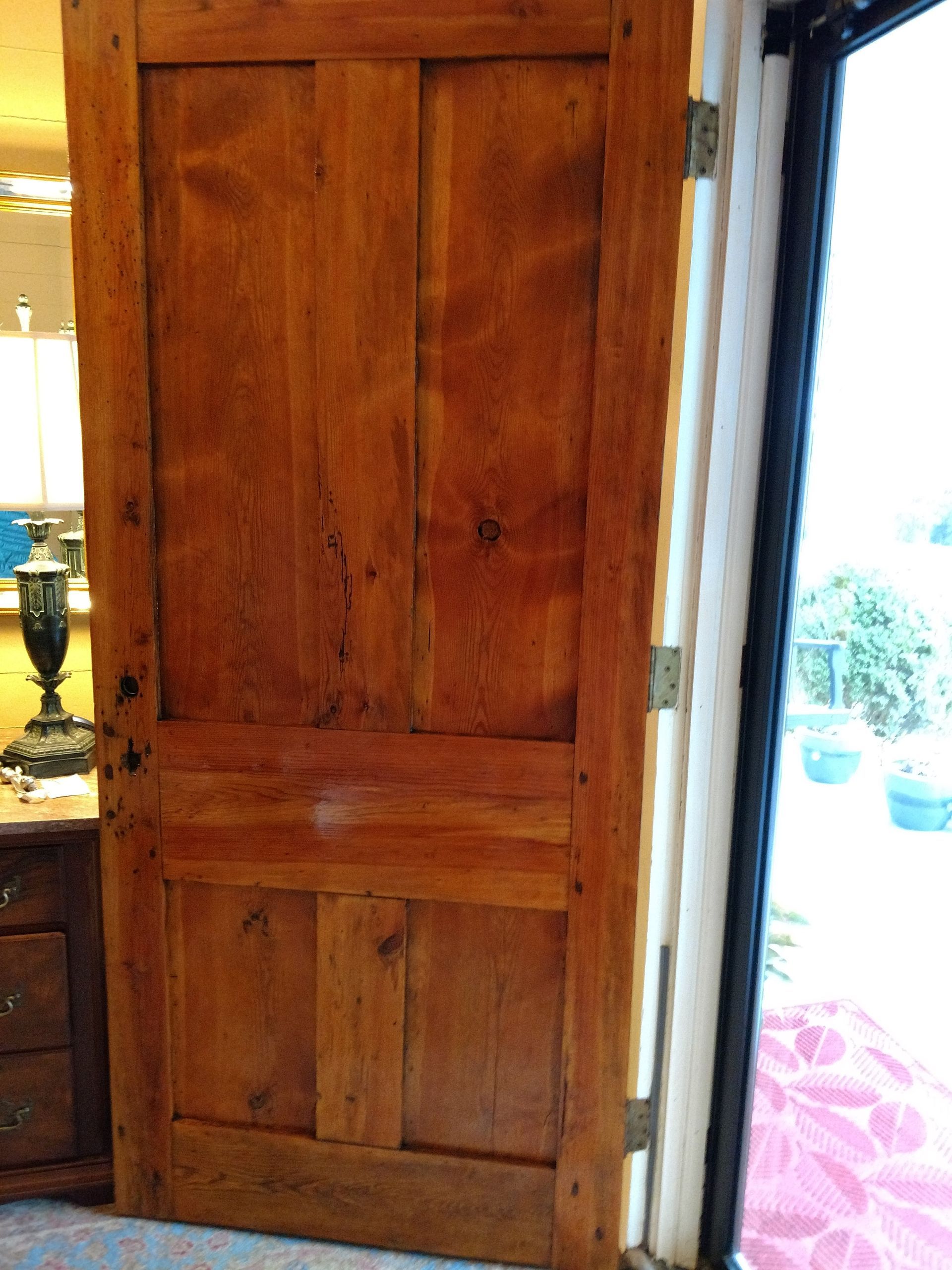 Wooden door, brown with vertical planks and horizontal crossbars, hinges on the right, opening to outside.