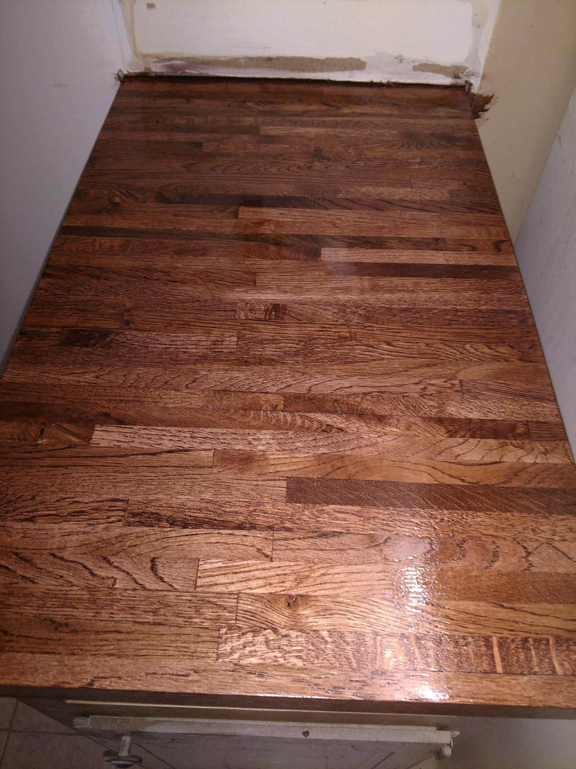 Close-up of a stained wooden countertop with varying shades of brown planks.