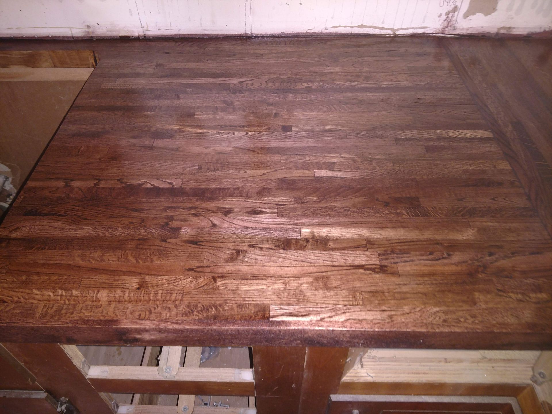 Wooden countertop, dark brown, with visible wood grain and imperfections.