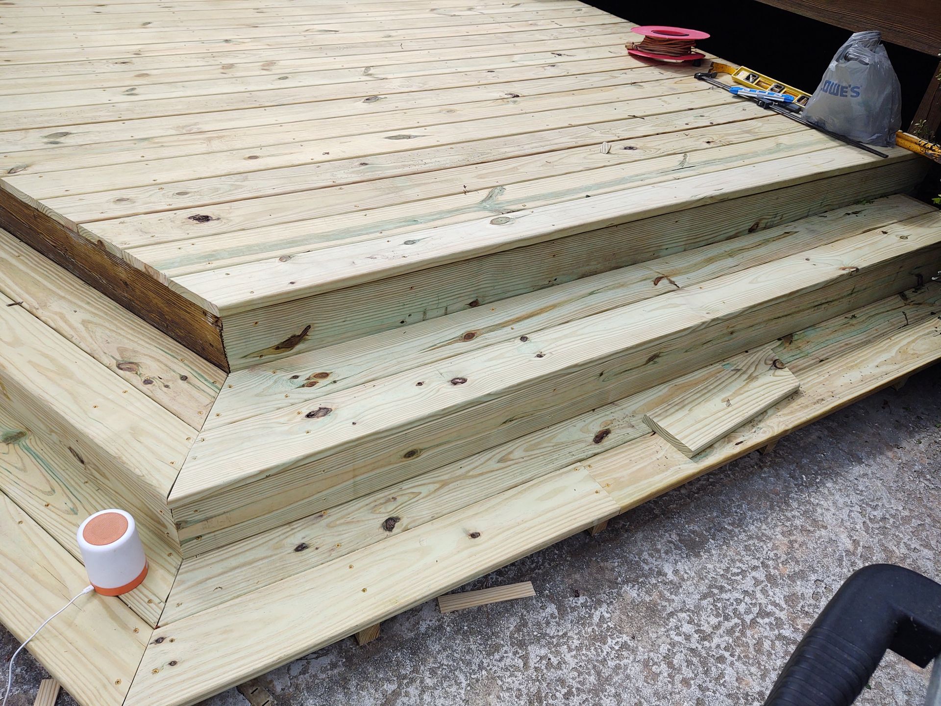 Wooden deck with three steps under construction, angled edge, light wood.