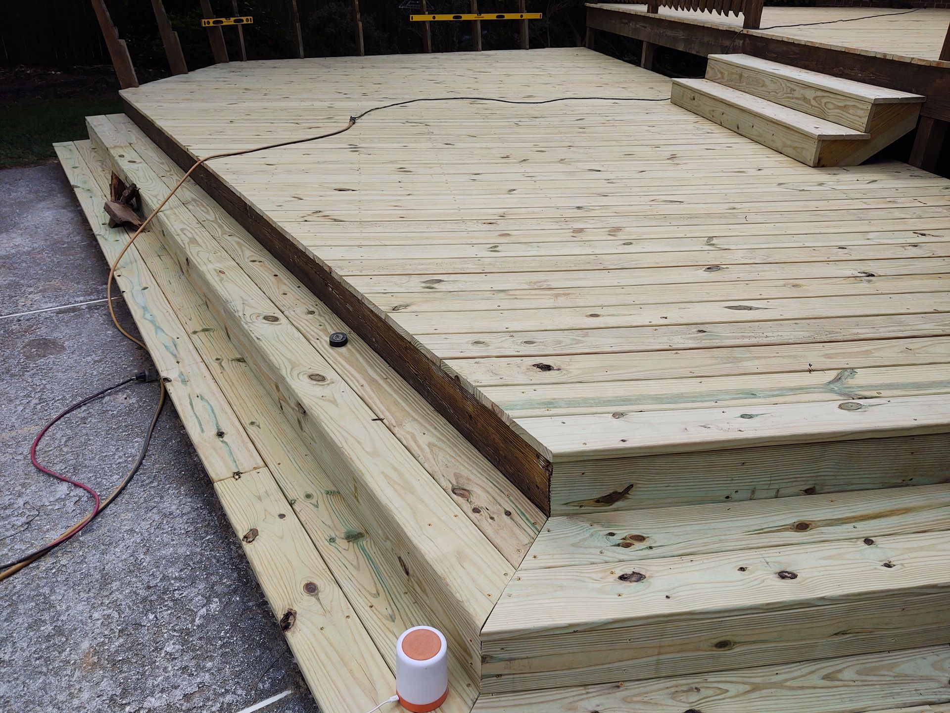 Wooden deck with steps, partially built. Electrical cord and supplies visible.