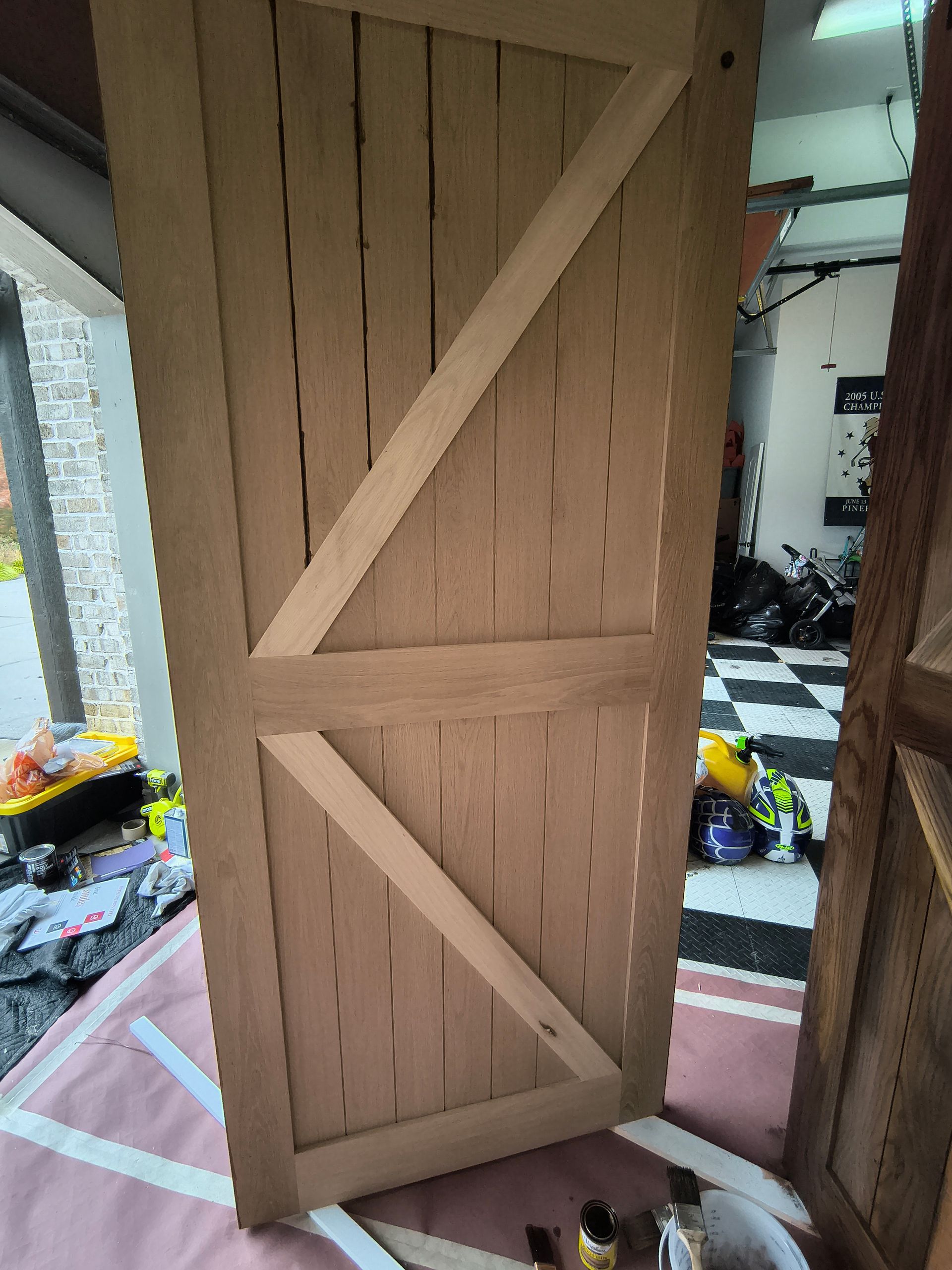 Wooden barn door with diagonal support beams, inside a garage.