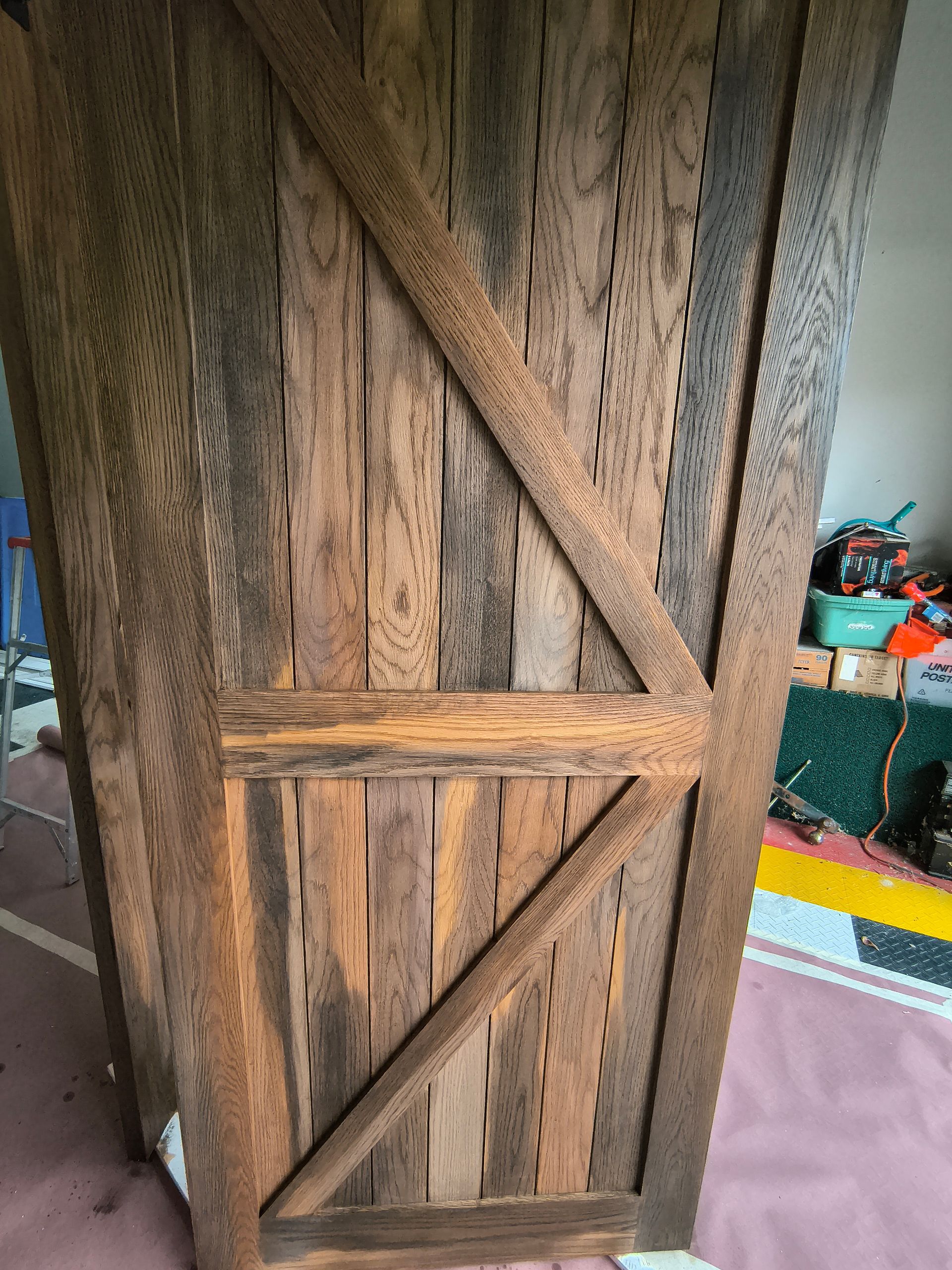 Wooden barn door with diagonal support, stained in various shades of brown.