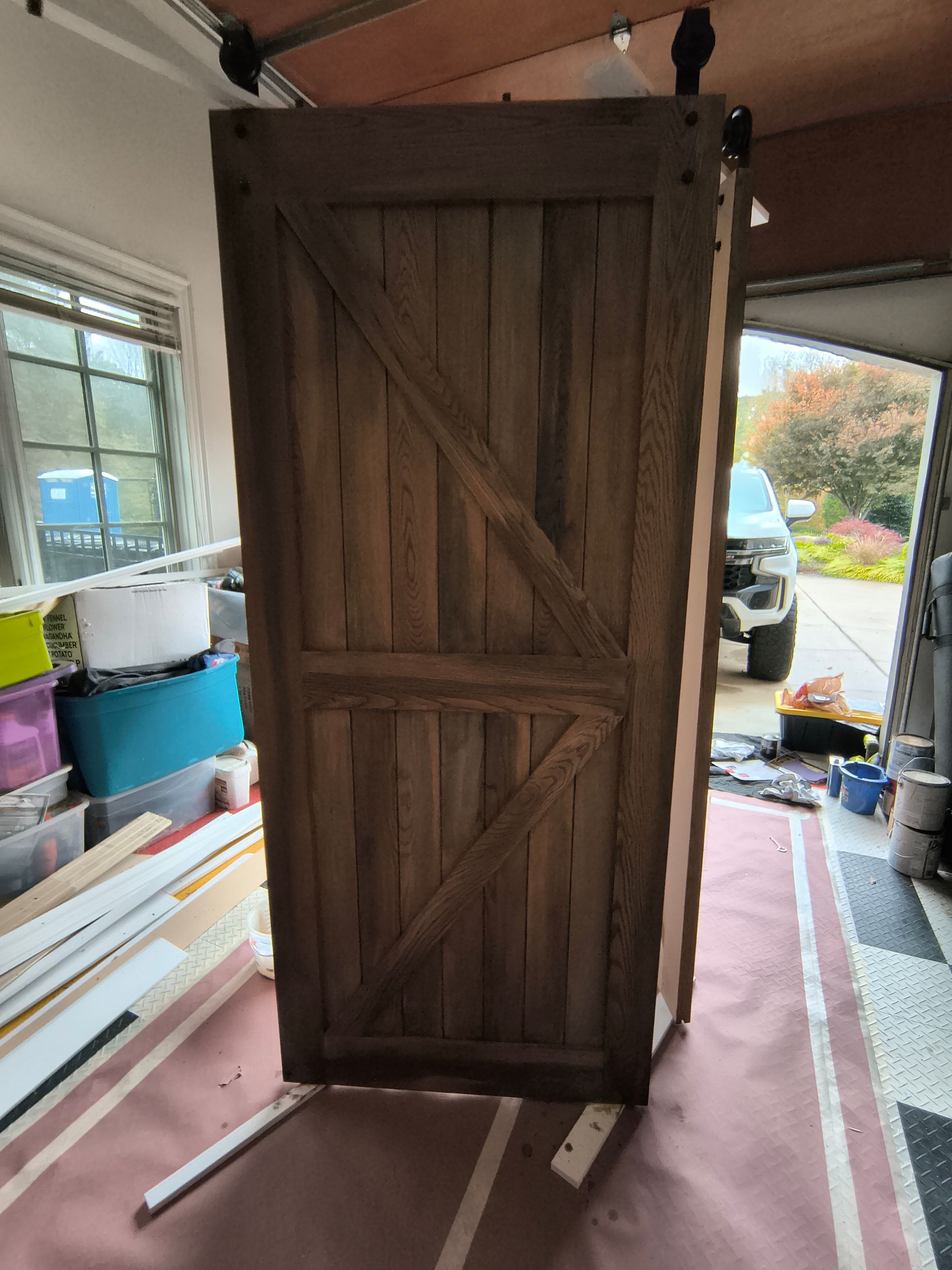 Wooden barn door with diagonal brace, indoors, partially open garage.