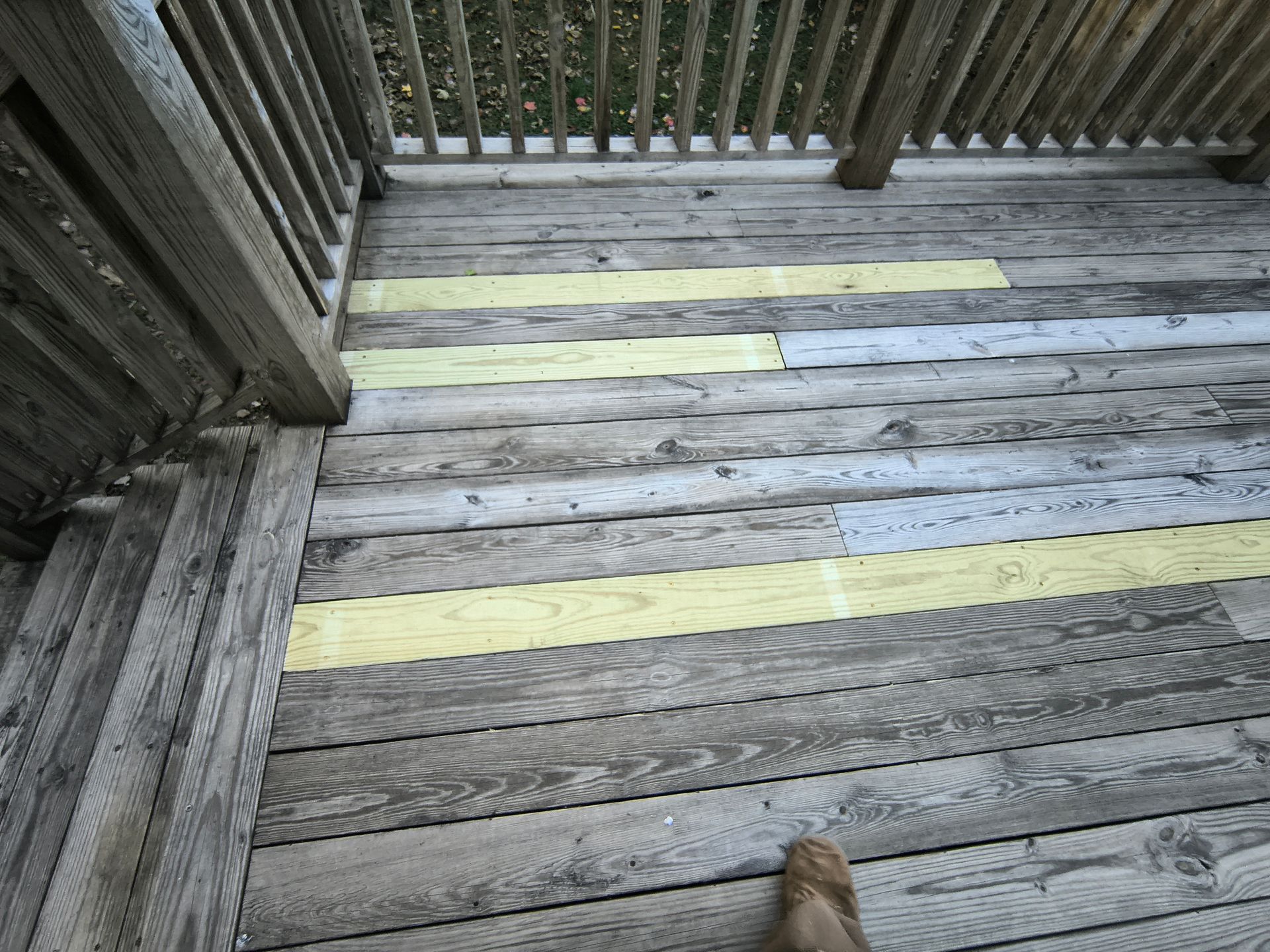 Wooden deck with yellow painted stripes. A foot is visible.