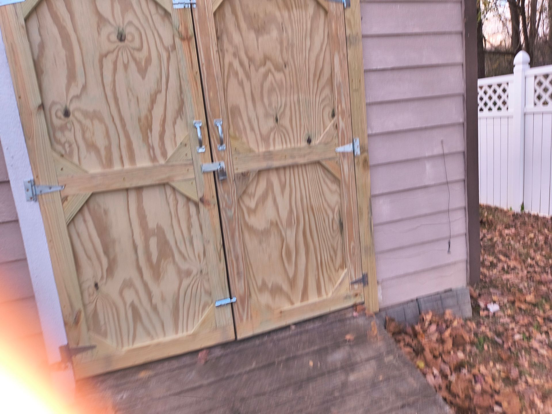 Wooden shed doors with hinges, latches, and a ramp.