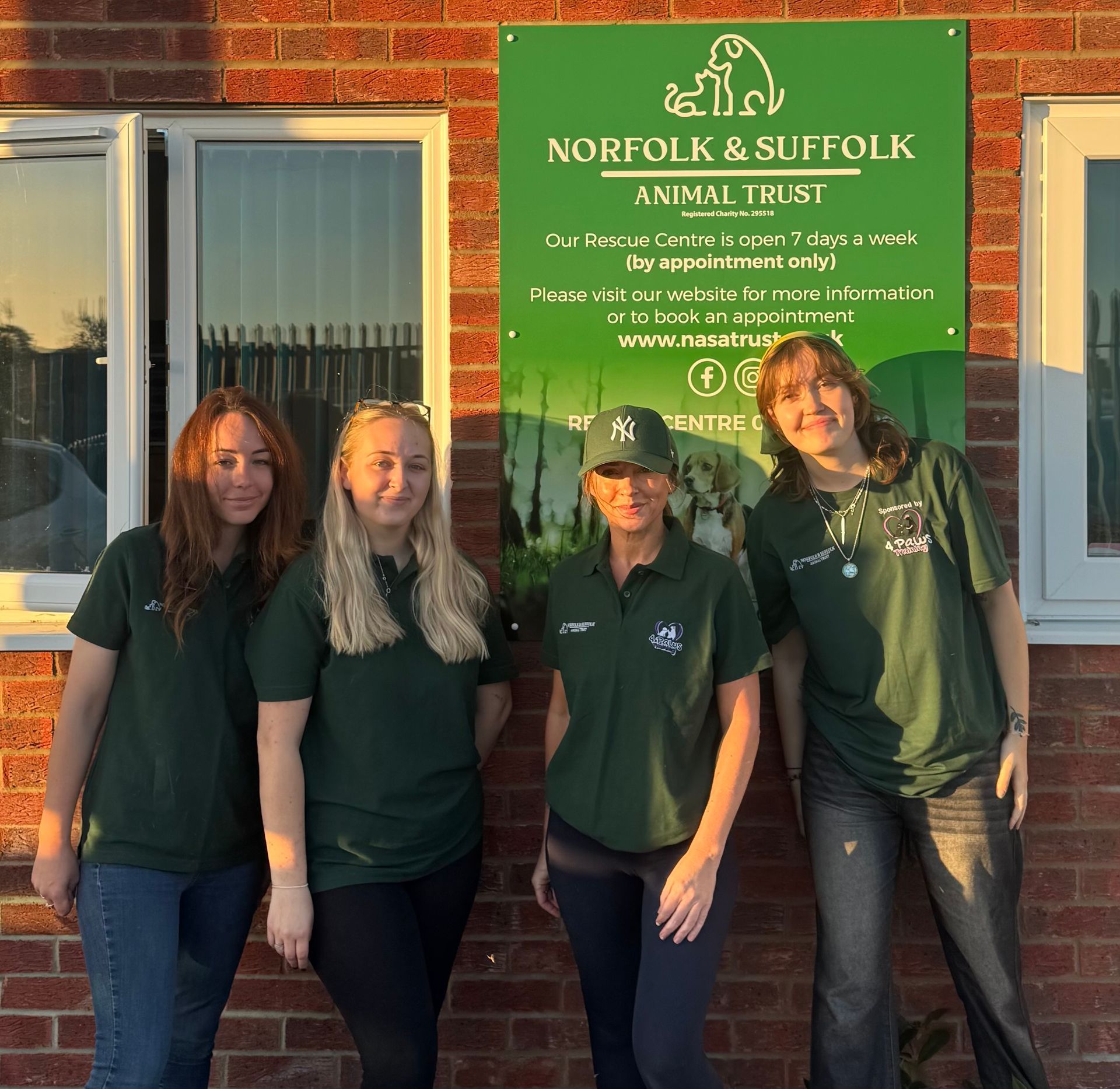 Woman with blonde hair and glasses smiles, wearing a red shirt, in front of floral art.