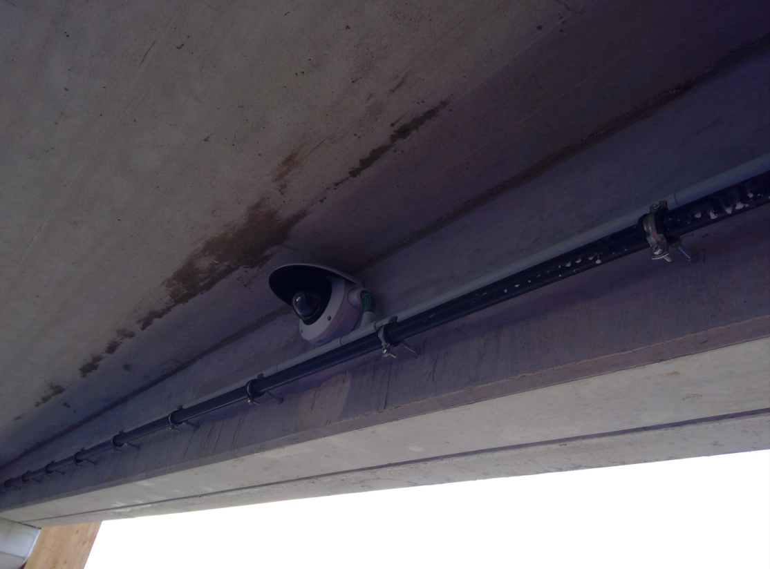 Une caméra de sécurité est suspendue au plafond d'un bâtiment.