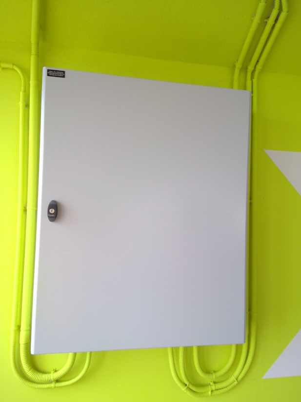 Une boîte blanche est accrochée sur un mur jaune.