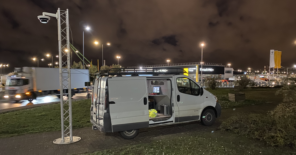 Une camionnette blanche est garée sur un parking la nuit.