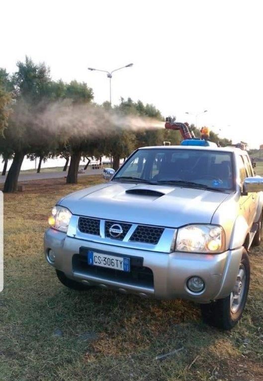 Un pick-up Nissan argentato spruzza nebbia all'aperto.