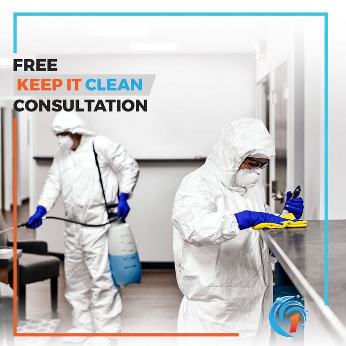 Two men in protective suits are cleaning a counter.