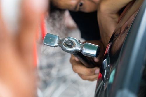 mechanic hammering the auto body