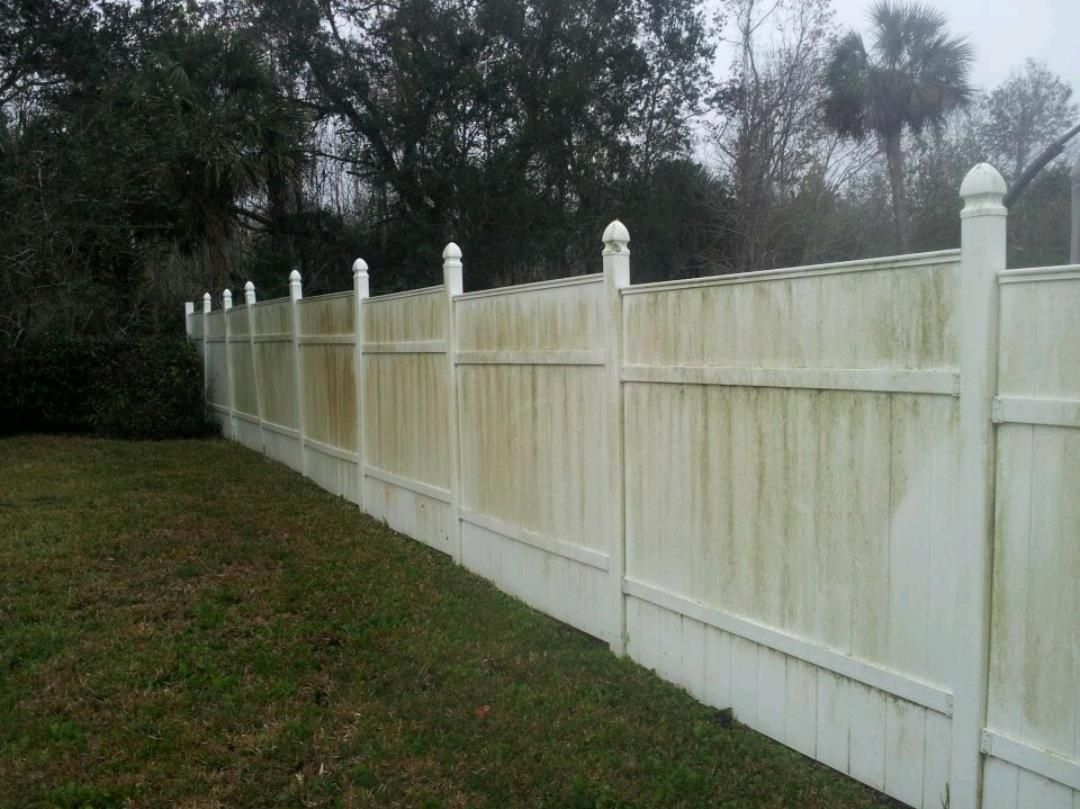 High-pressure water cleaning being applied to a wooden fence.