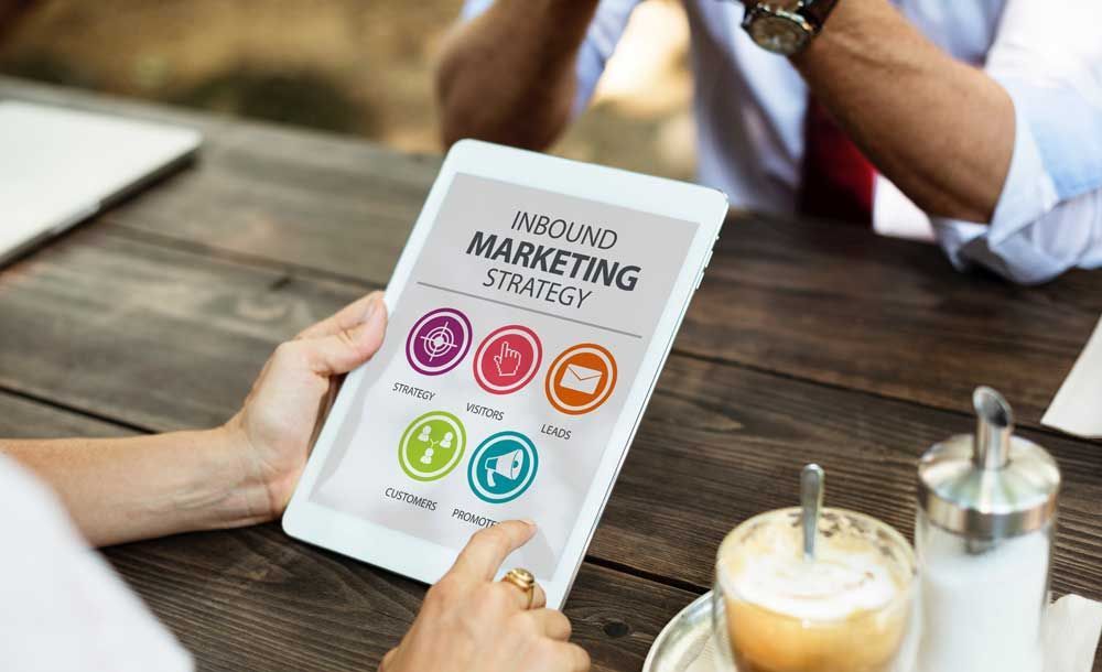 A person is holding a tablet with inbound marketing strategy on it.