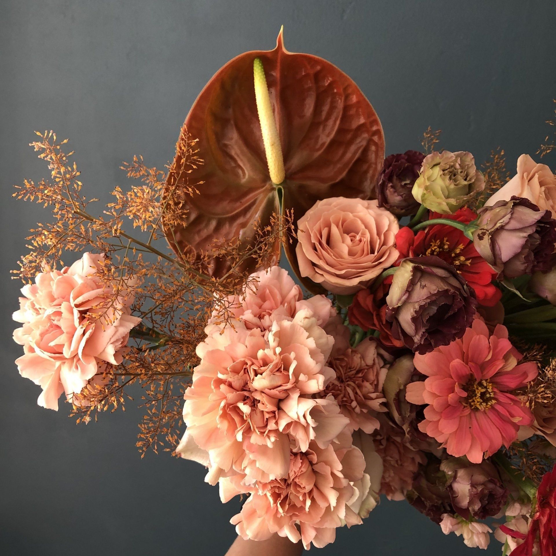 A floral arrangement featuring a calla lily, carnations, roses, and zinnias