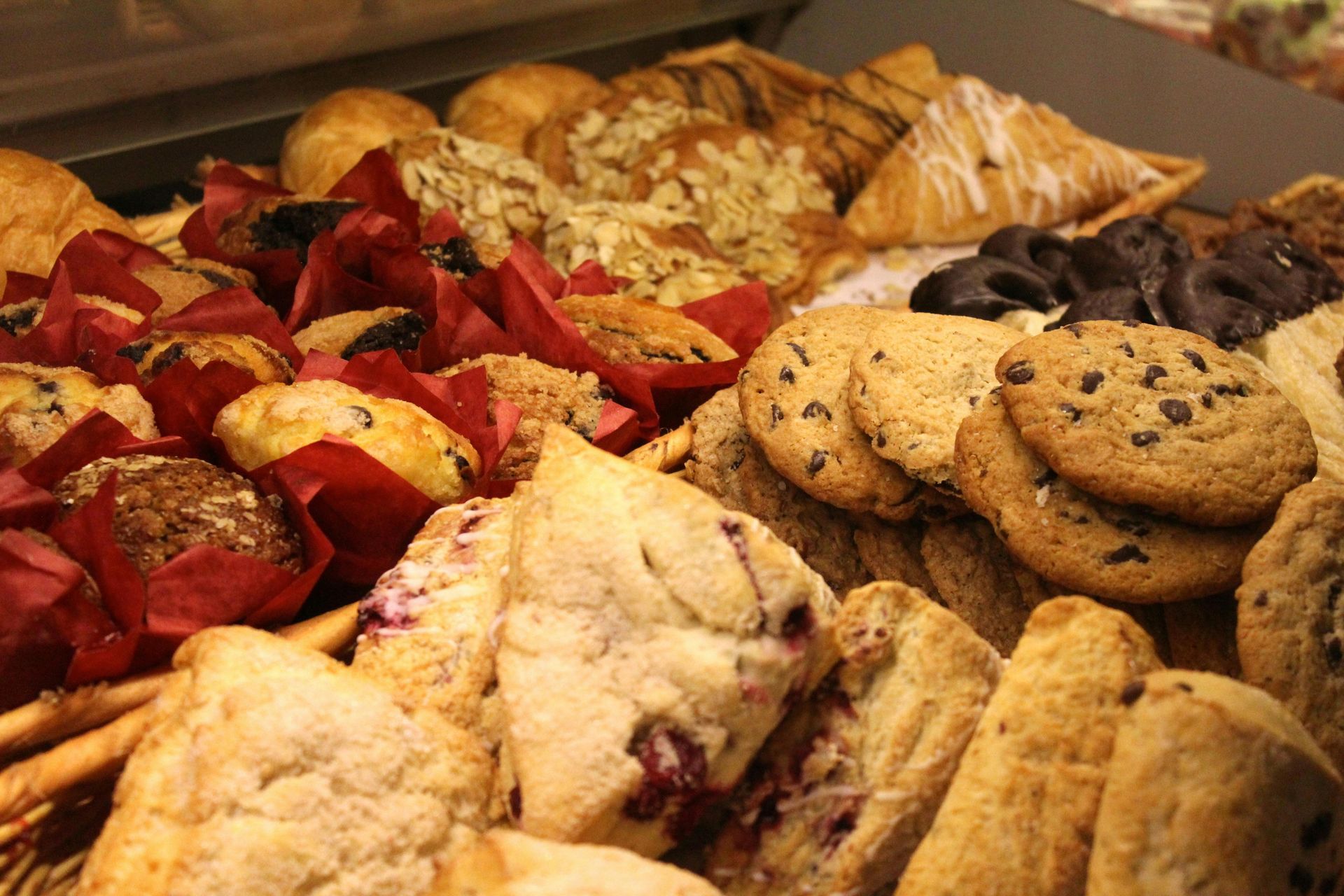 Assorted baked goods, including cookies, muffins, scones, and pastries, displayed in a bakery case.