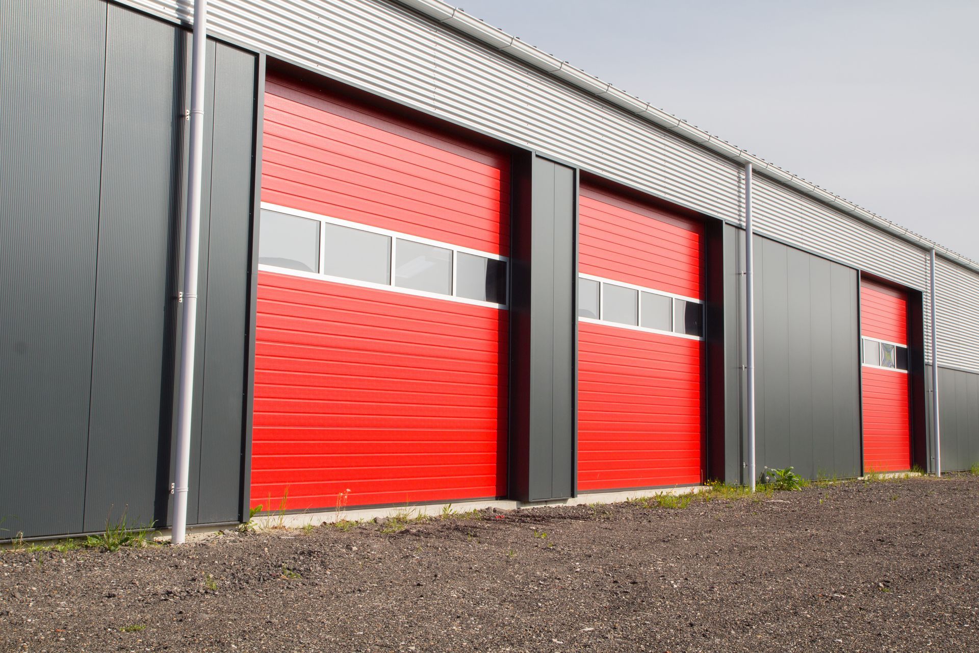 Row of red commercial garage doors on an industrial building.