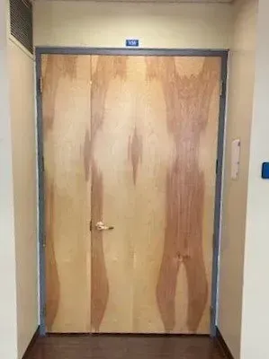 A wooden door in a hallway with a shadow of a person on it.