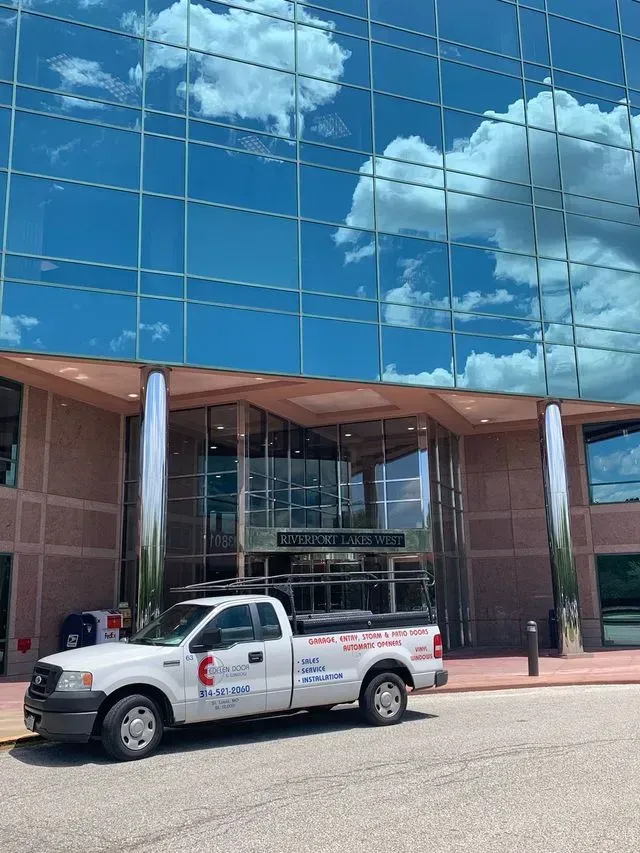 A white truck is parked in front of a large building.