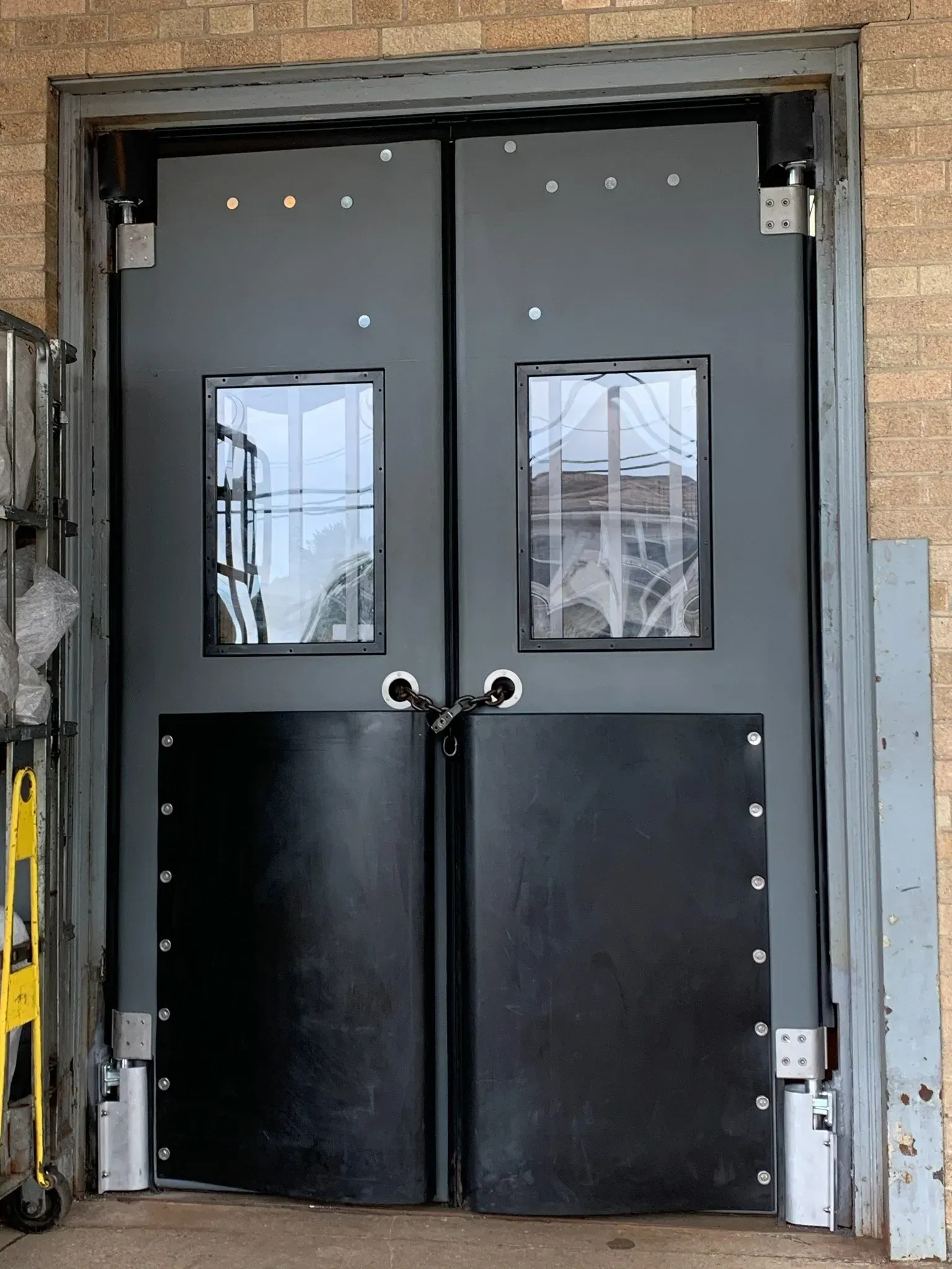 A pair of black doors with a brick wall behind them