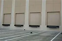 A row of loading docks on the side of a building in a parking lot.