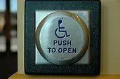 A push to open button with a wheelchair symbol on it.
