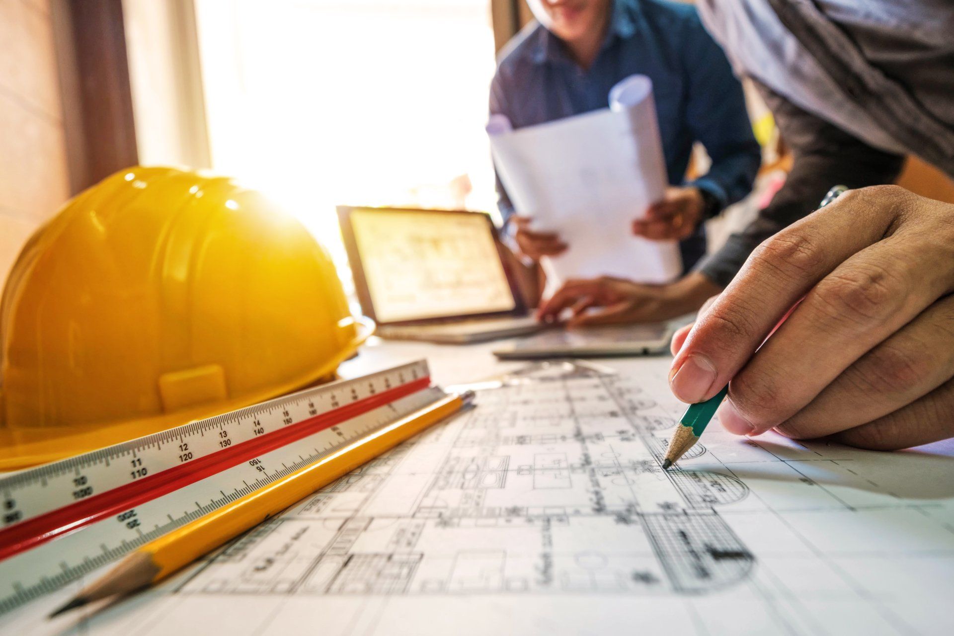 Two colleagues discussing data working and tablet, laptop with on on architectural project at construction site at desk in office