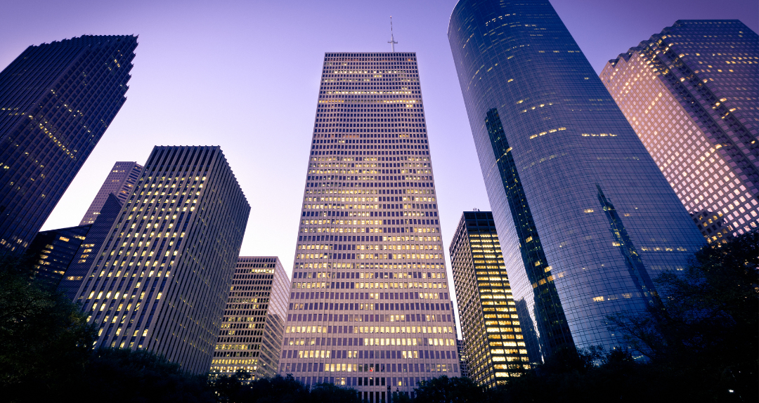 A city skyline at night with a purple sky in the background