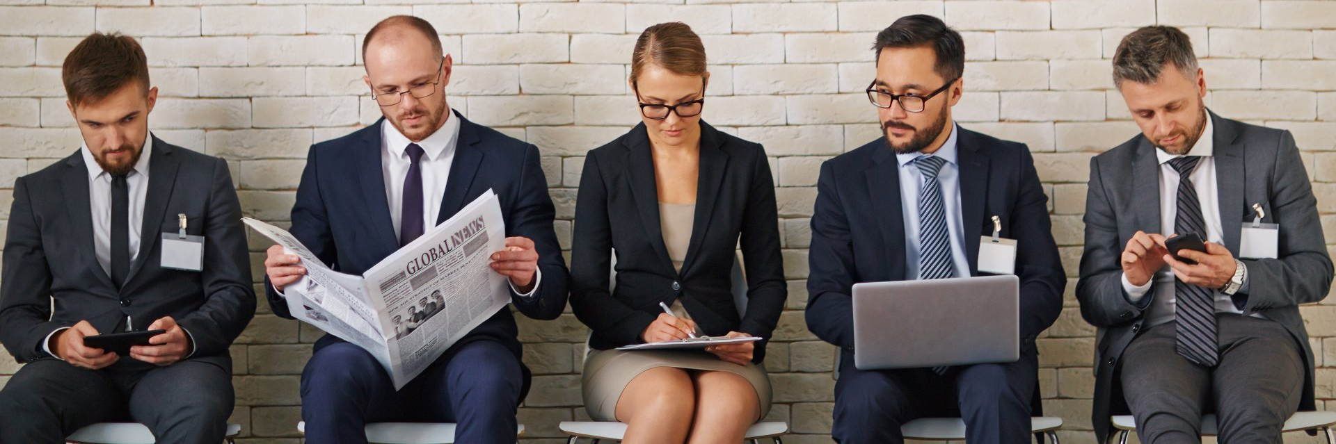 A group of business people are sitting in a row waiting for a job interview.