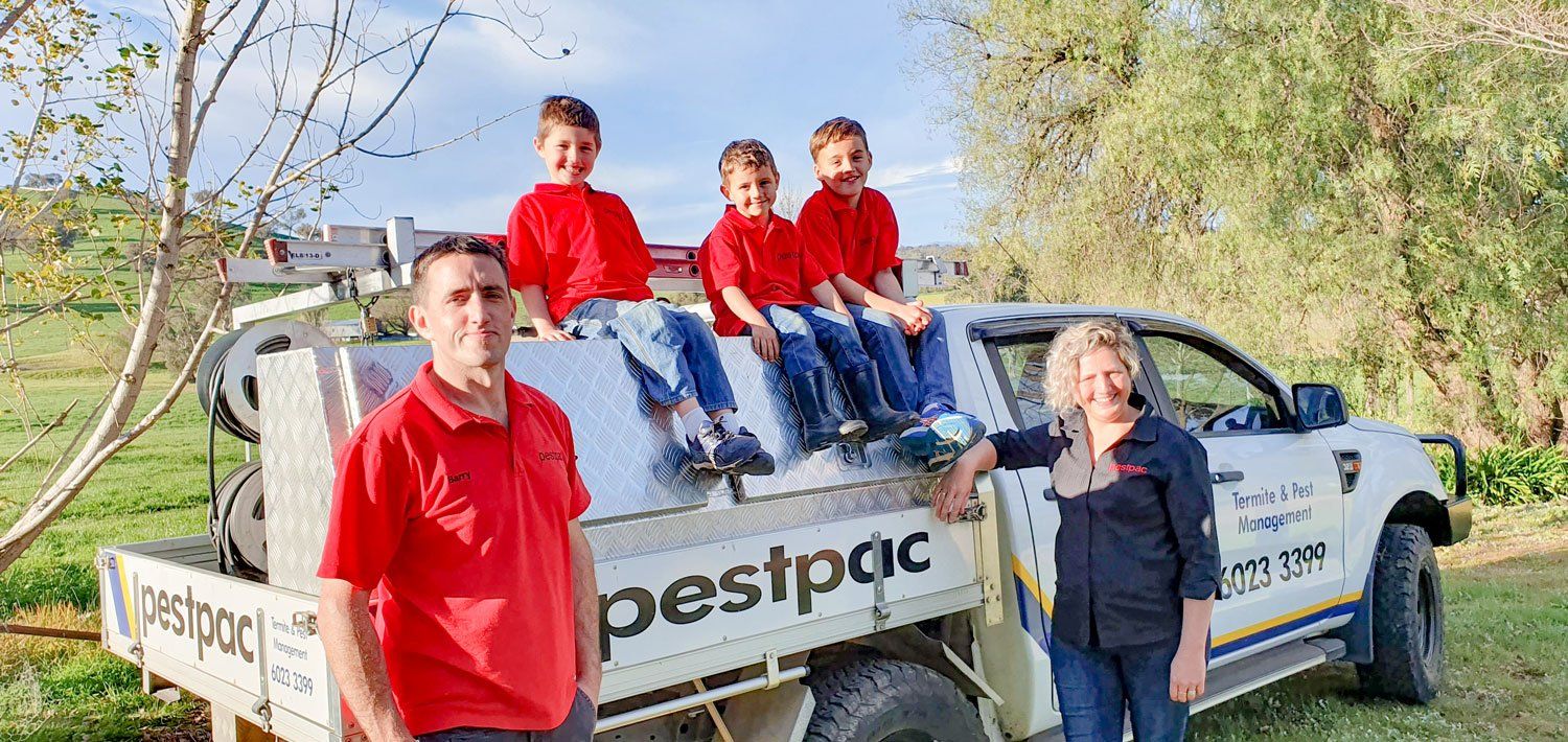 A group of people standing in front of a Pestpac truck.