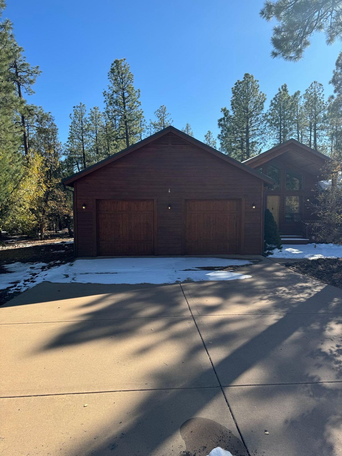 A large wooden garage with a driveway in front of it